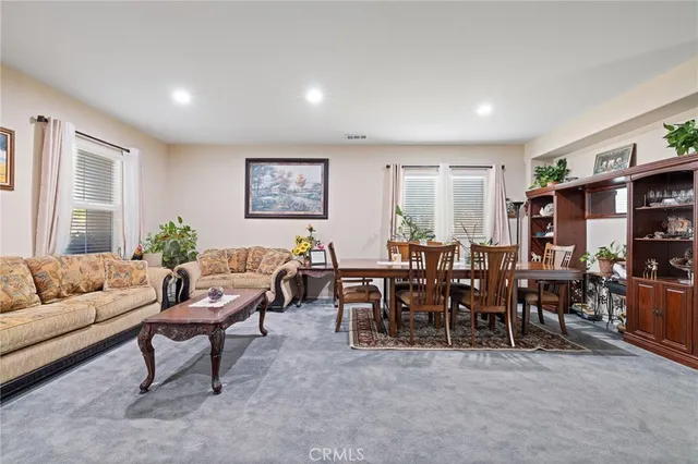 a living room with furniture potted plant kitchen view and a window