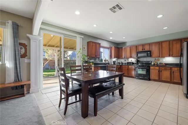a kitchen with stainless steel appliances granite countertop a refrigerator a sink a stove a dining table and chairs