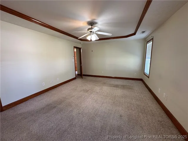 an empty room with a chandelier fan and windows