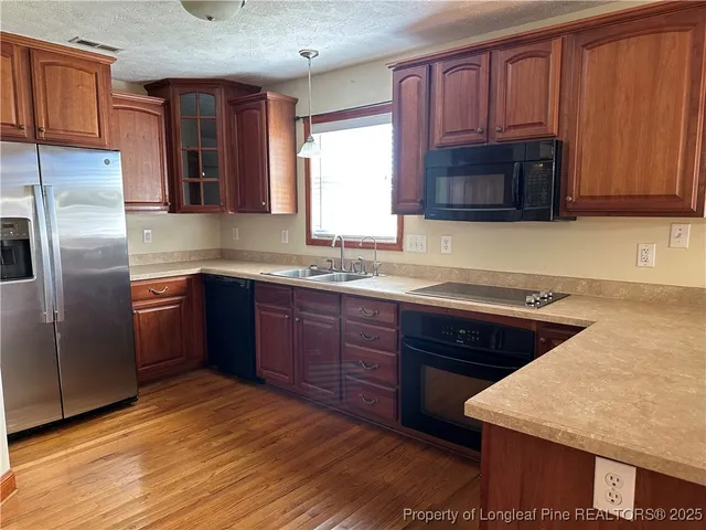 a kitchen with stainless steel appliances granite countertop a sink dishwasher stove and microwave with wooden cabinets