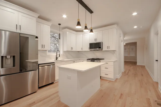 a kitchen with kitchen island a white counter top space stainless steel appliances and cabinets