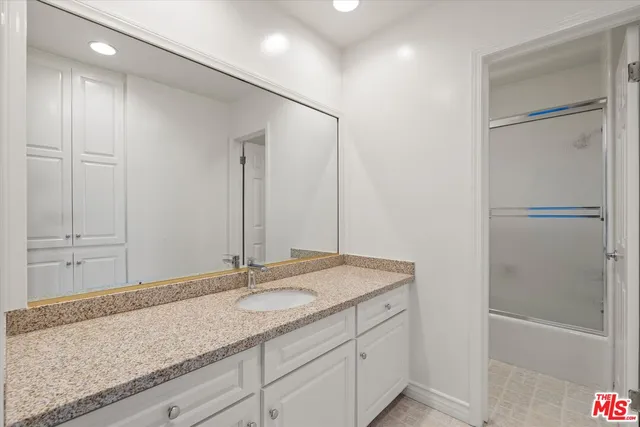 a bathroom with a granite countertop sink and a mirror