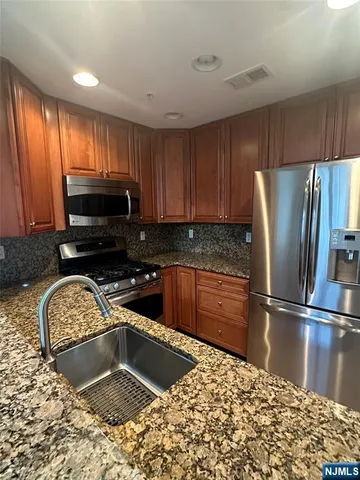 a kitchen with stainless steel appliances granite countertop a sink stove and refrigerator