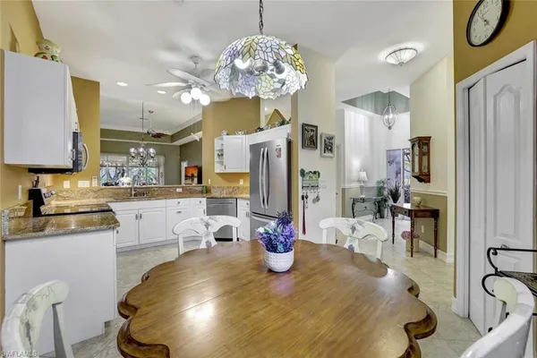 a kitchen with stainless steel appliances granite countertop a refrigerator a sink dishwasher a dining table and chairs with wooden floor