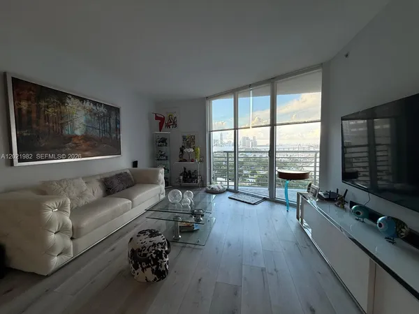 a living room with furniture flat screen tv and a large window