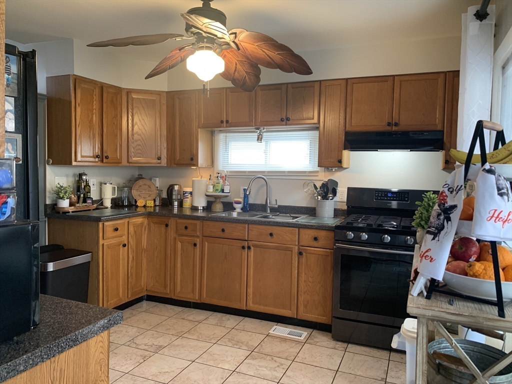 149 Smith Street Fall River, MA 02721 - Photo 8 of 38 a kitchen with granite countertop a stove a sink and dishwasher wooden cabinets
