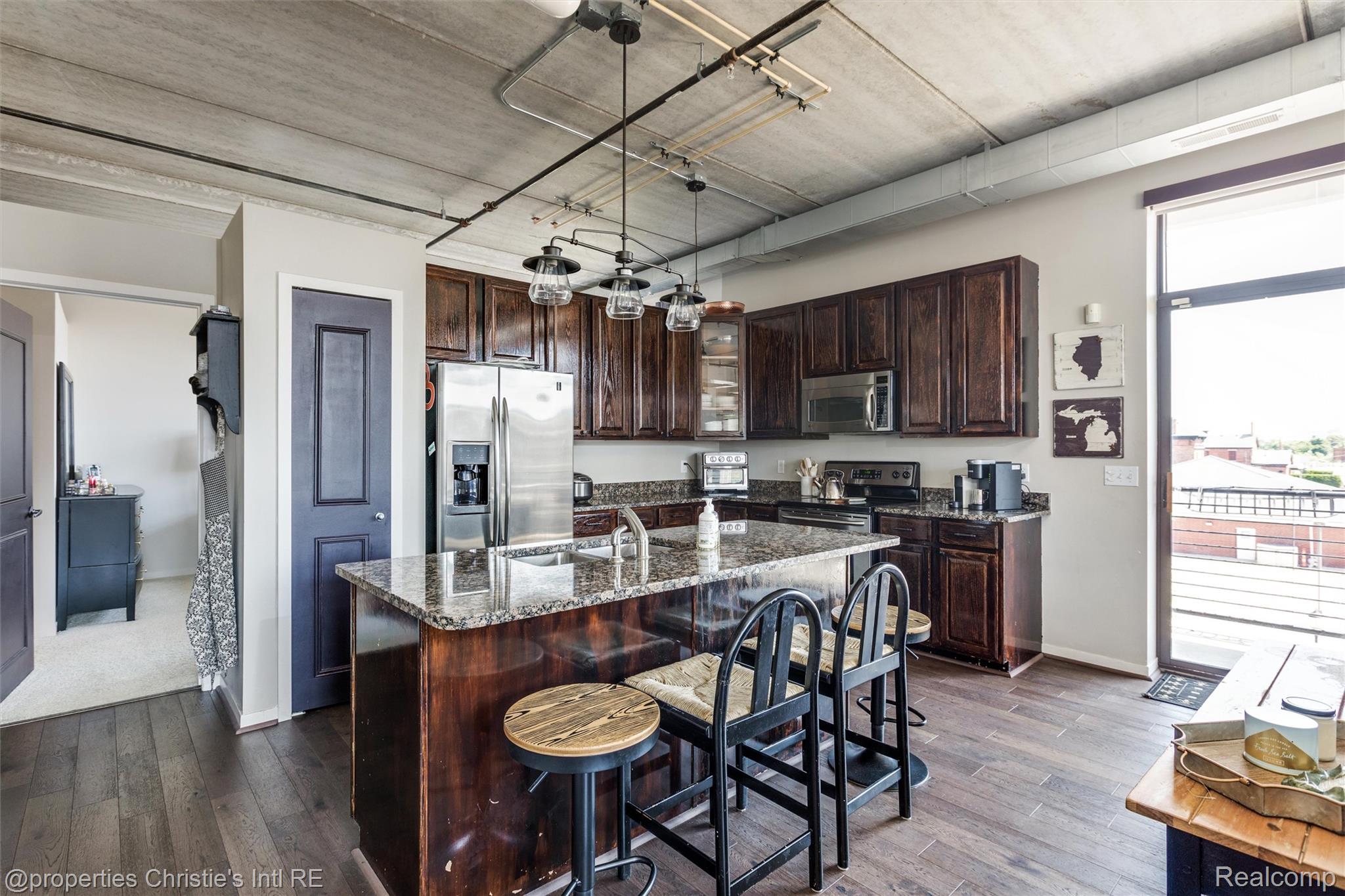 66 Winder Street, Unit 332 Detroit, MI 48201 - Photo 9 of 30 Kitchen with dark wood finish cabinets, dark wood-type flooring, stainless steel appliances, and an island with sink