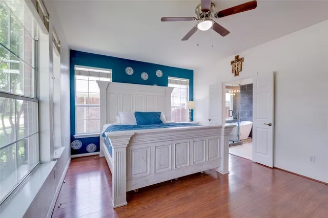 a spacious bedroom with a large bed and a chandelier fan
