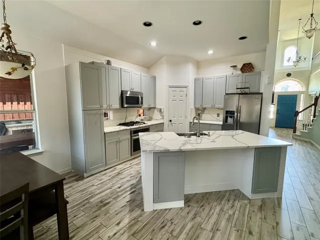 a kitchen with kitchen island a sink stainless steel appliances and cabinets