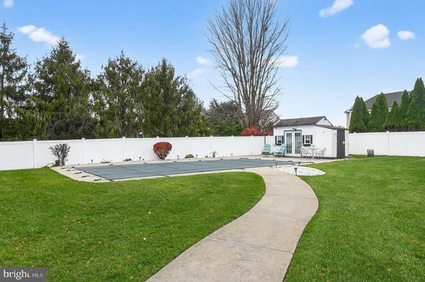 a view of a white house with a big yard plants and large trees