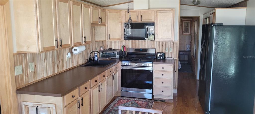 4421 Lane Road, Unit 216B Zephyrhills, FL 33541 - Photo 6 of 22 a kitchen with stainless steel appliances a refrigerator a sink and white cabinets