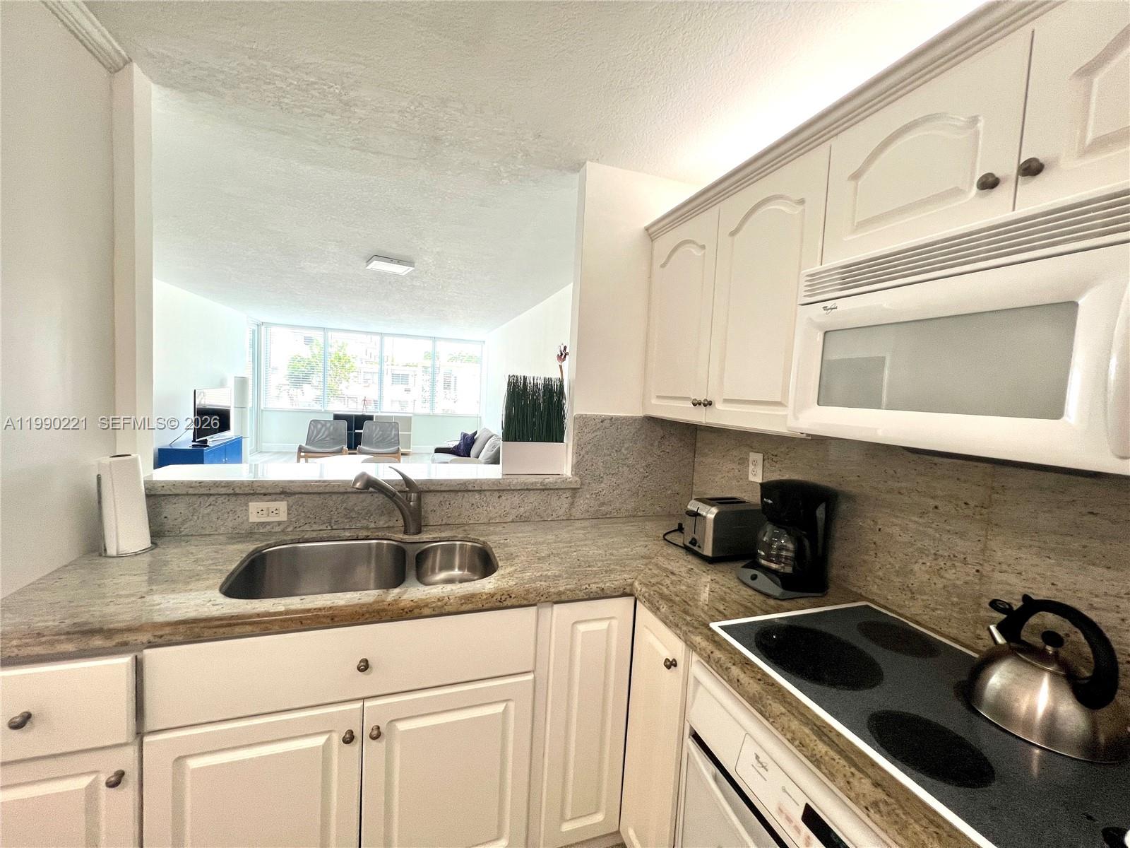 8233 Harding Avenue, Unit 204 Miami Beach, FL 33141 - Photo 1 of 18 a kitchen with granite countertop a sink and cabinets