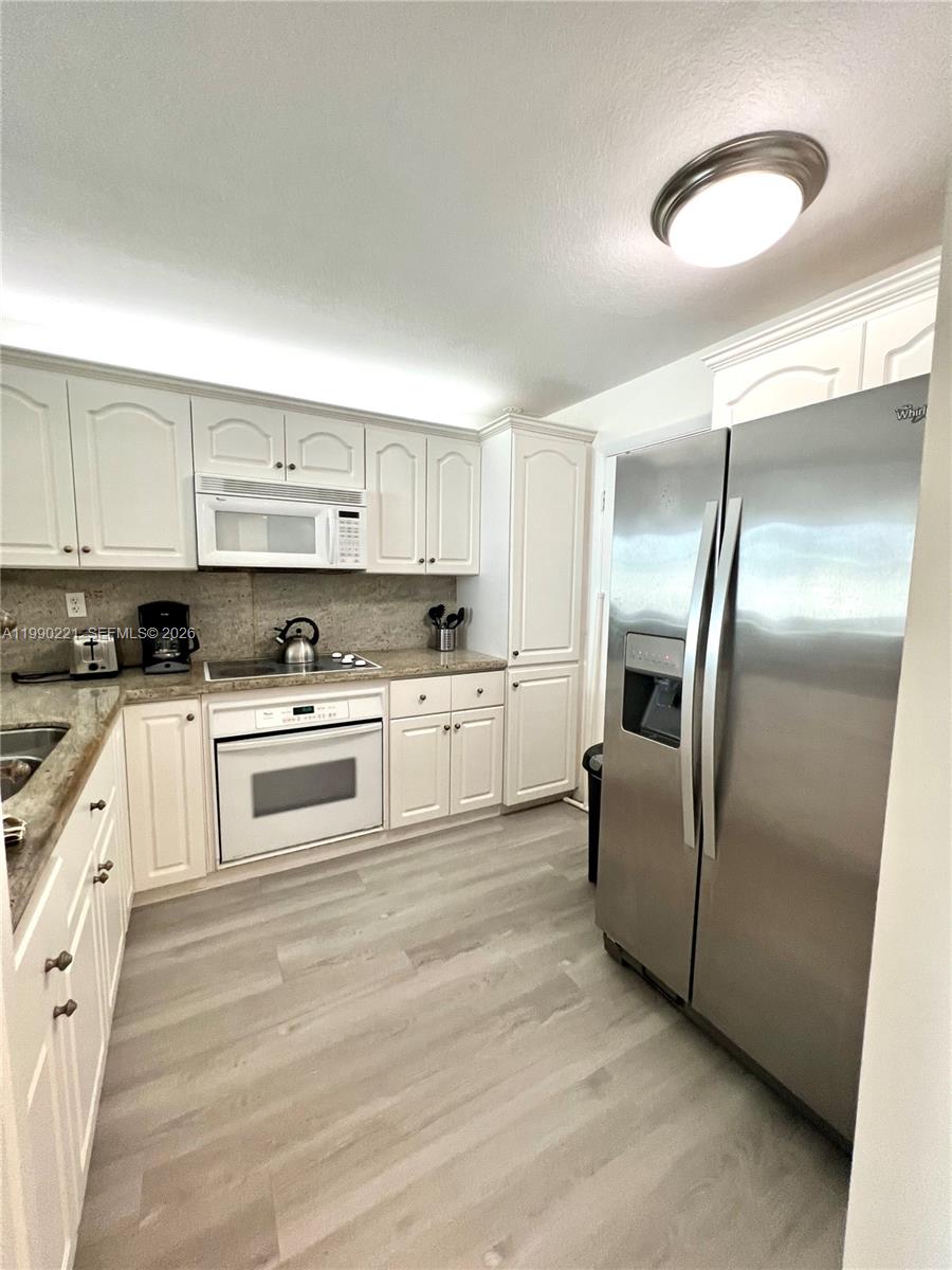 8233 Harding Avenue, Unit 204 Miami Beach, FL 33141 - Photo 2 of 18 a kitchen with cabinets stainless steel appliances and a counter top space