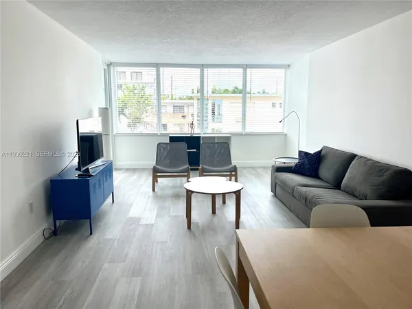 a living room with furniture a flat screen tv and a large window