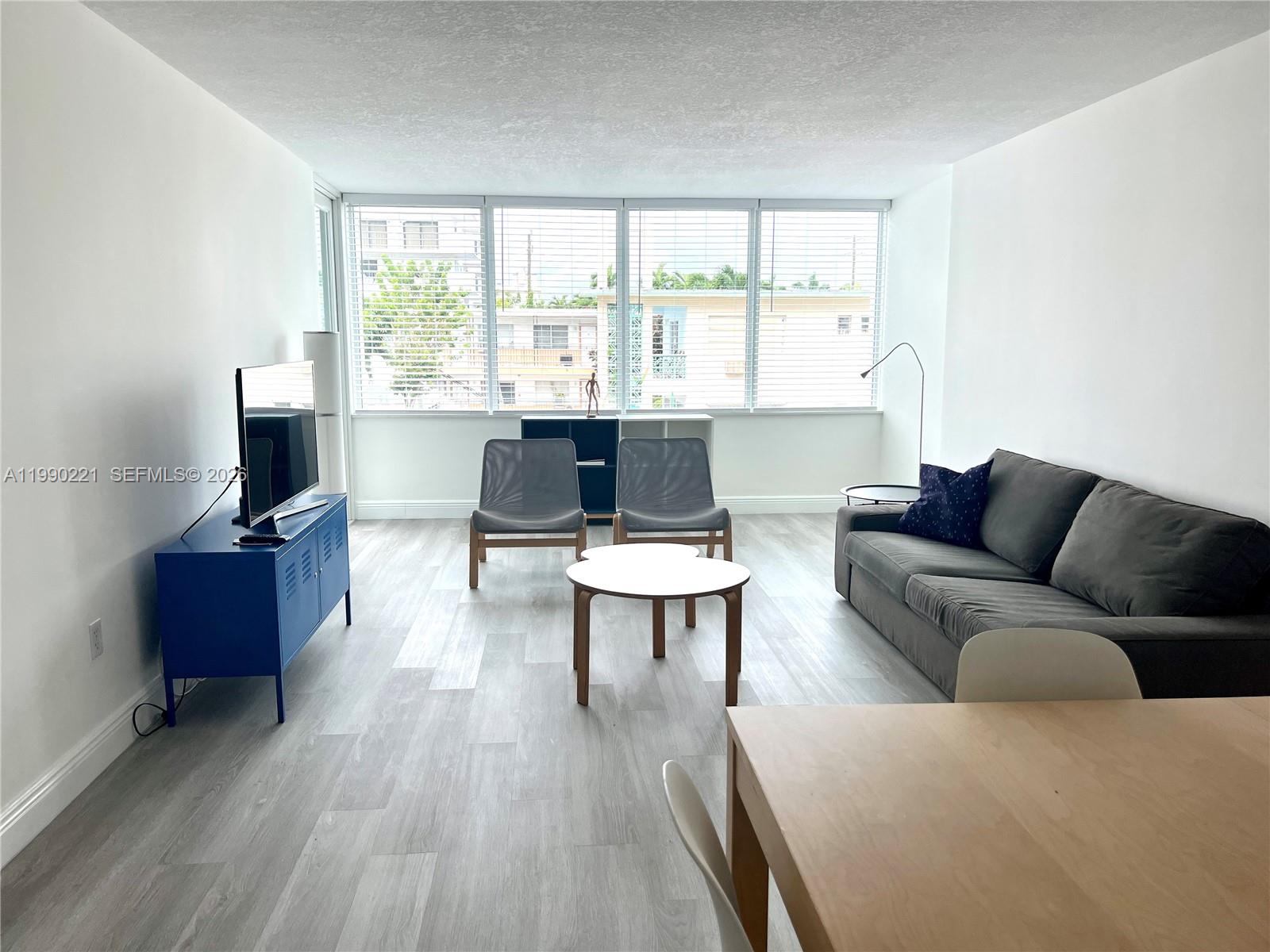 8233 Harding Avenue, Unit 204 Miami Beach, FL 33141 - Photo 8 of 18 a living room with furniture a flat screen tv and a large window