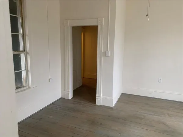 a view of an empty room with wooden floor and closet