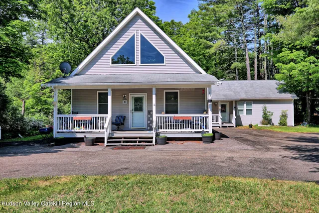 a front view of a house with swing plants and large trees