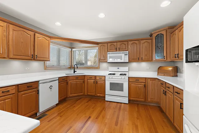 a kitchen with a sink cabinets wooden floor and stainless steel appliances