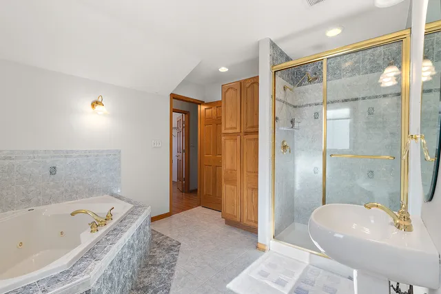 a bathroom with a tub shower sink and mirror