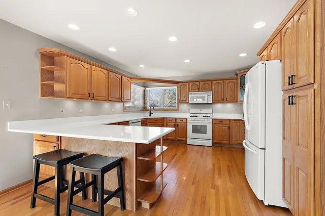 a kitchen with stainless steel appliances granite countertop wooden floor a refrigerator a sink dishwasher and a stove with wooden floor