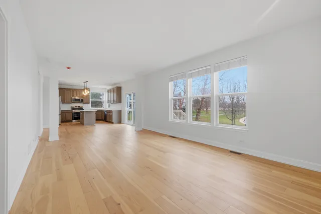 a view of empty room with wooden floor and windows