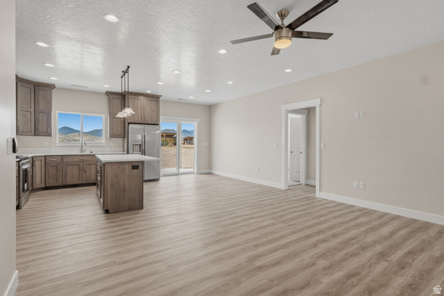169 West 100 South Joseph, UT 84739 - Photo 12 of 35 Kitchen featuring a kitchen island, light countertops, stainless steel appliances, a textured ceiling, and light wood finished floors
