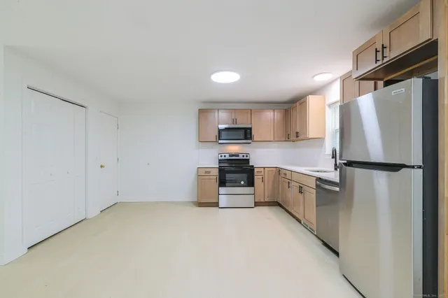 a kitchen with a refrigerator a stove top oven and cabinets