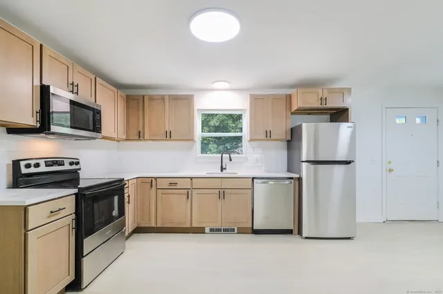 a kitchen with stainless steel appliances granite countertop a refrigerator sink and stove