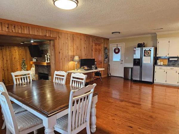 a kitchen with stainless steel appliances granite countertop a stove top oven a sink a dining table and chairs with wooden floor