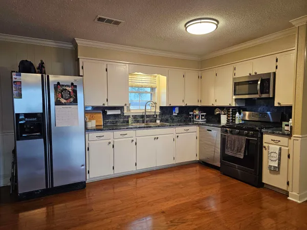 a kitchen with stainless steel appliances granite countertop a refrigerator a stove a sink and a microwave