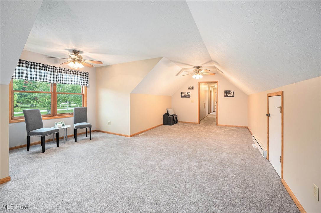 2073 Sexton Road Austinburg, OH 44010 - Photo 21 of 32 Bonus room featuring a textured ceiling, ceiling fan, a baseboard radiator, light colored carpet, and lofted ceiling