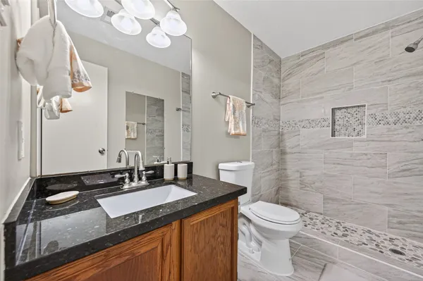 a bathroom with a granite countertop sink a toilet and a mirror