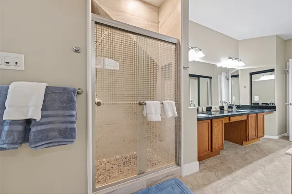 a bathroom with a granite countertop sink a mirror and shower