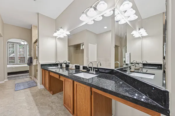 a large bathroom with a granite countertop double vanity sink a mirror and bathtub