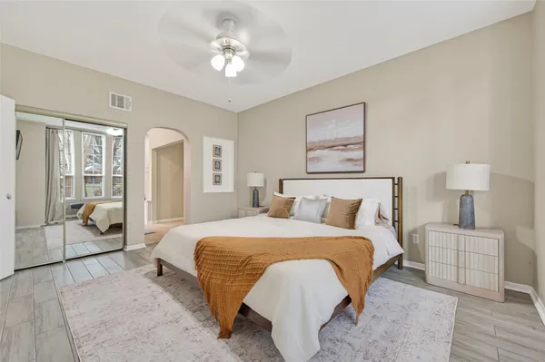 a bedroom with a large bed couch and two windows