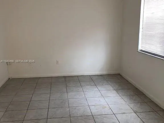an empty room with a white cabinet and a window