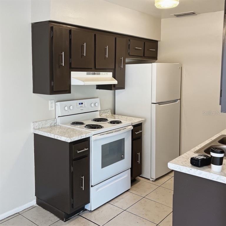 5200 Curry Ford Road, Unit 102 Orlando, FL 32812 - Photo 4 of 23 a kitchen with a refrigerator sink stove and cabinets