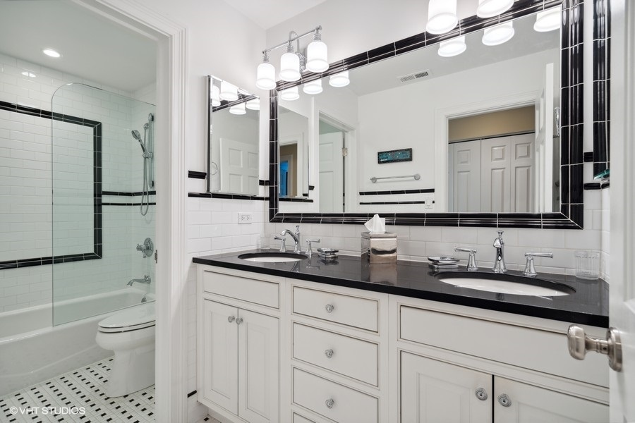 1335 North Sutton Place Chicago, IL 60610 - Photo 19 of 31 a bathroom with a granite countertop sink a toilet a mirror and shower