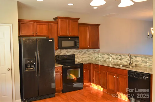 a kitchen with granite countertop a refrigerator stove and oven with wooden floor