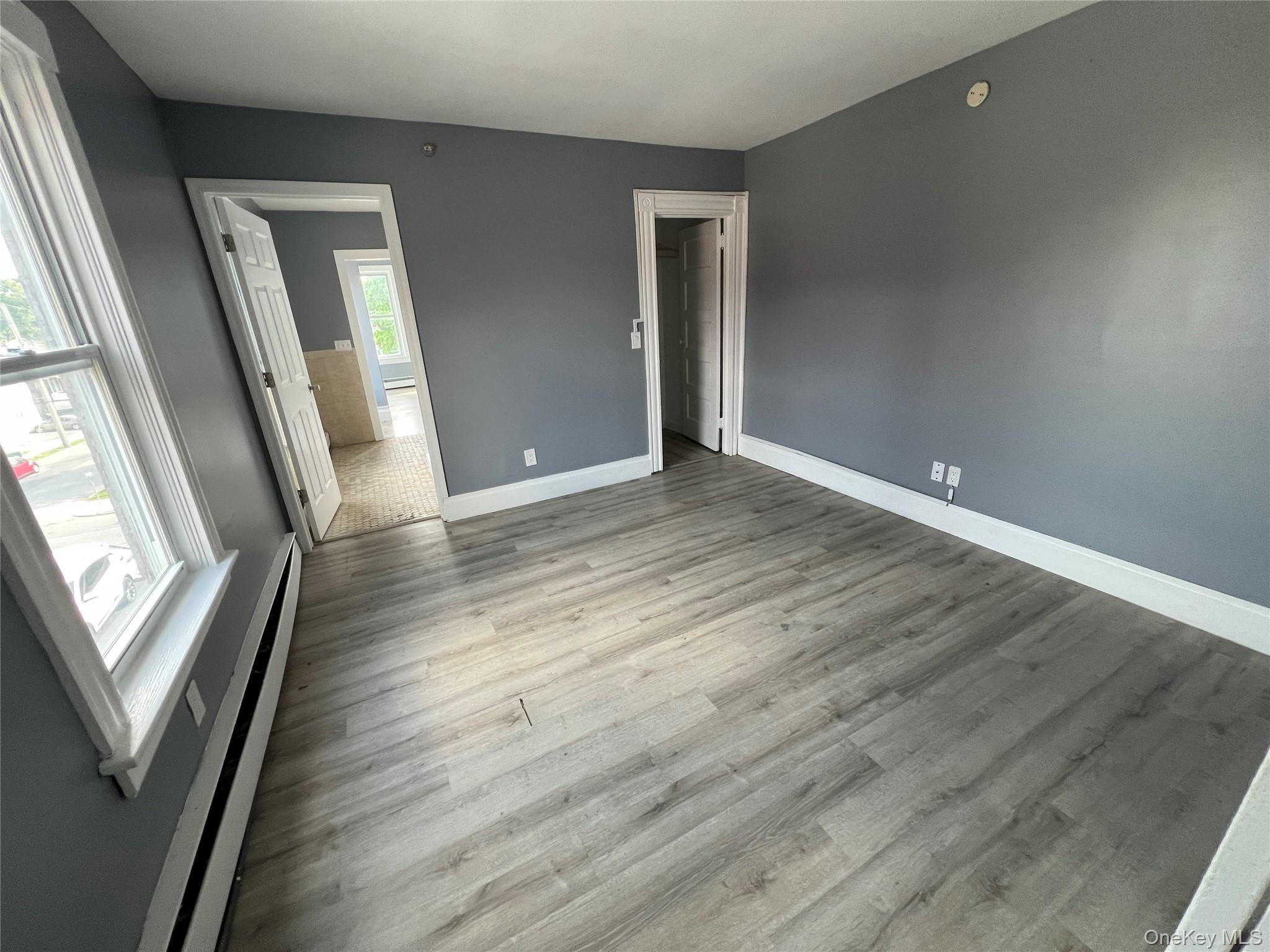 761 Main Street, Unit 3E Poughkeepsie, NY 12603 - Photo 6 of 8 an empty room with wooden floor and mirror