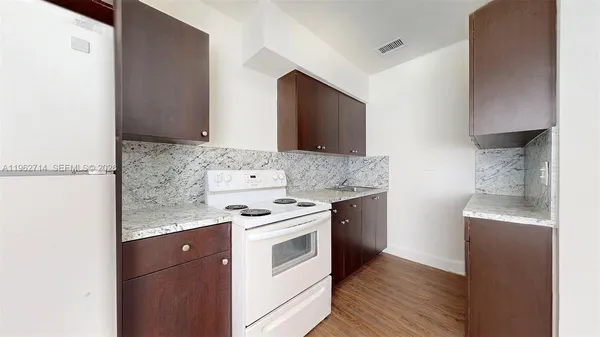 a kitchen with granite countertop a sink a stove and a wooden floors