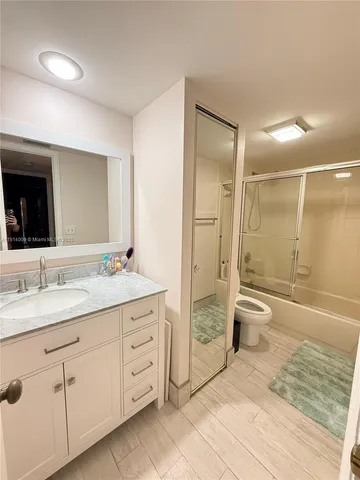 a spacious bathroom with a granite countertop sink toilet mirror and bathtub