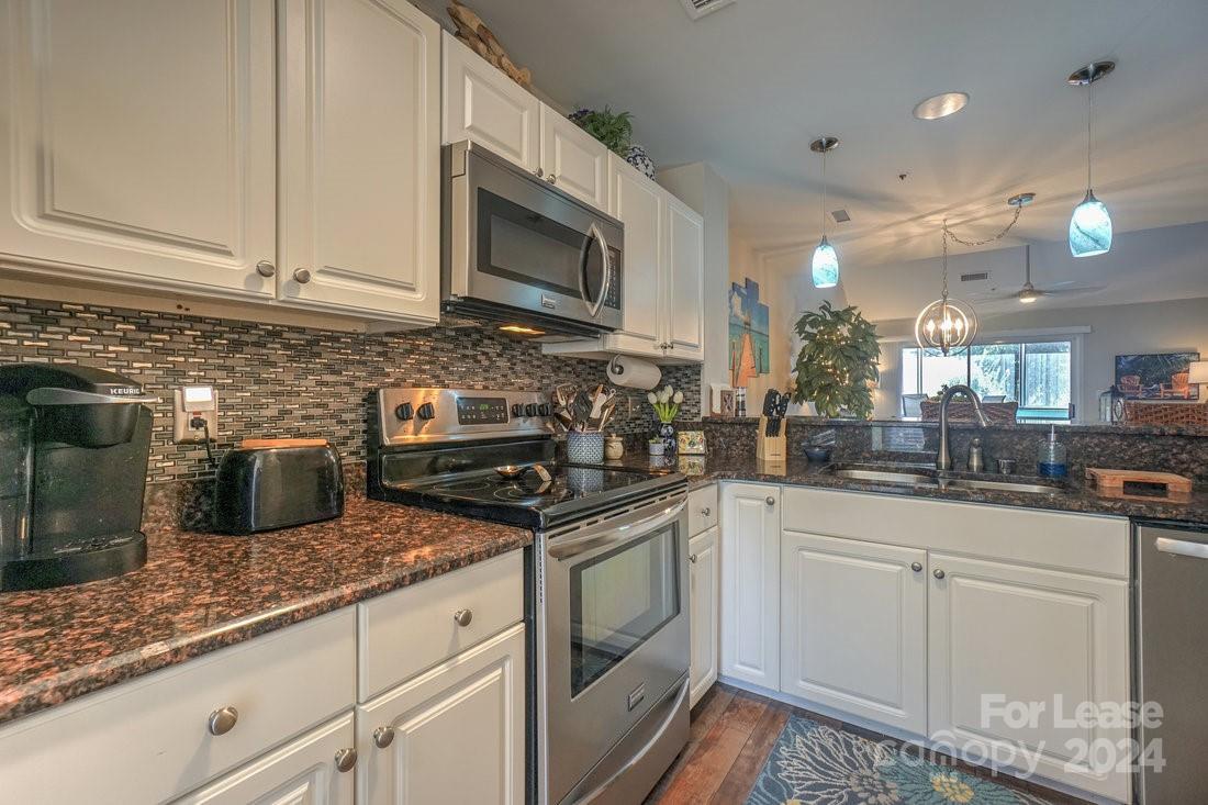 17542 Tuscany Lane Cornelius, NC 28031 - Photo 7 of 35 a kitchen with stainless steel appliances granite countertop a sink a stove and a microwave
