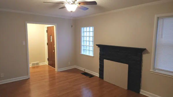 a view of an empty room with wooden floor and a window