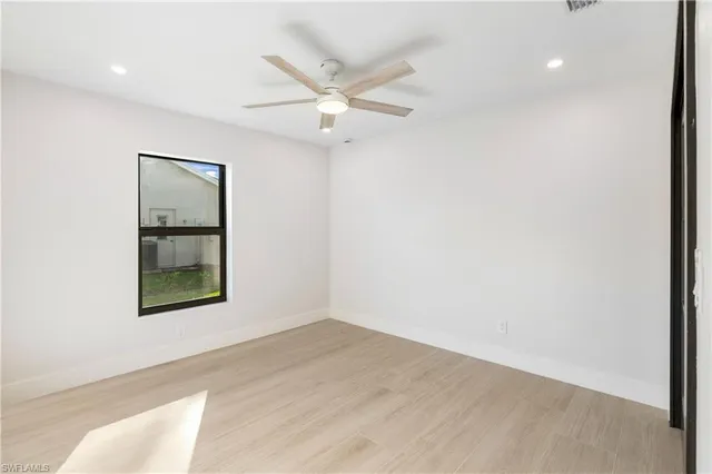 an empty room with a window and a ceiling fan