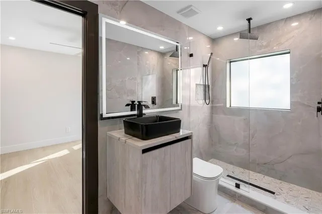 a bathroom with a sink a toilet a mirror and shower