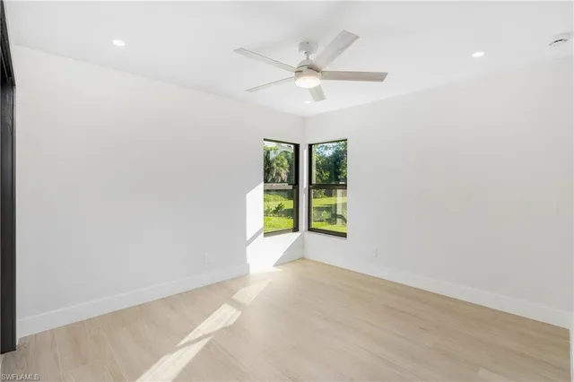 an empty room with windows and fan