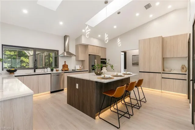 a kitchen with stainless steel appliances granite countertop a table chairs and a refrigerator