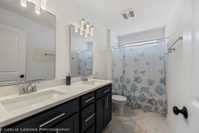 a bathroom with a double vanity sink mirror and toilet