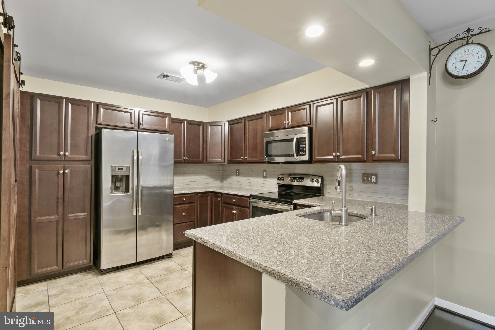 9802 Sailfish Terrace Gaithersburg, MD 20886 - Photo 4 of 18 a kitchen with kitchen island granite countertop a sink refrigerator and microwave